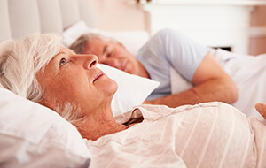 Senior woman lying awake in bed