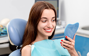 Woman looking at whitened teeth in mirror