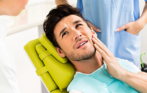 Man in dental chair holding cheek